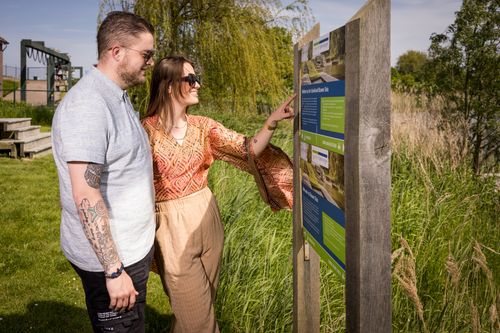 Man en vrouw kijken op informatiewandelbord bij Blauwe Sluis.