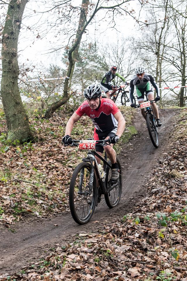 Drie personen op een mountainbike fietsen van een heuvel af in Zeist in regio De Utrechtse Heuvelrug.