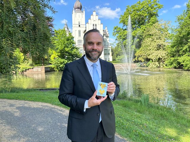 Wethouder Du Maine houdt de opvouwbare plattegrond van Visit Vught in zijn hand.