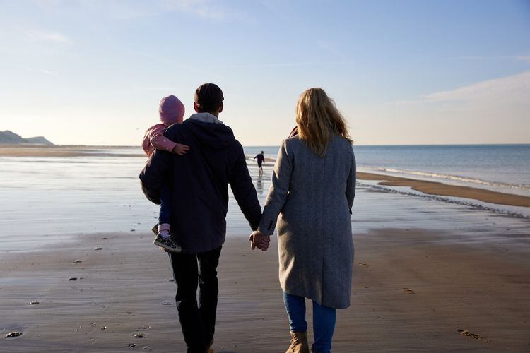 Op-Schouwen-Duiveland-Wandelen-Langs-De-Noordzee-Verliefd-Stel-Hand-In-Hand-Met-Kind-In-De-Armen