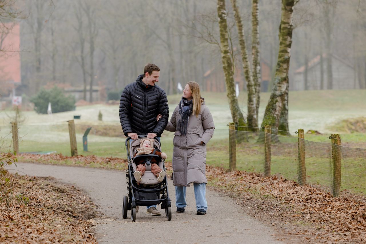 Man en vrouw wandelend met hun kind in de wandelwagen.