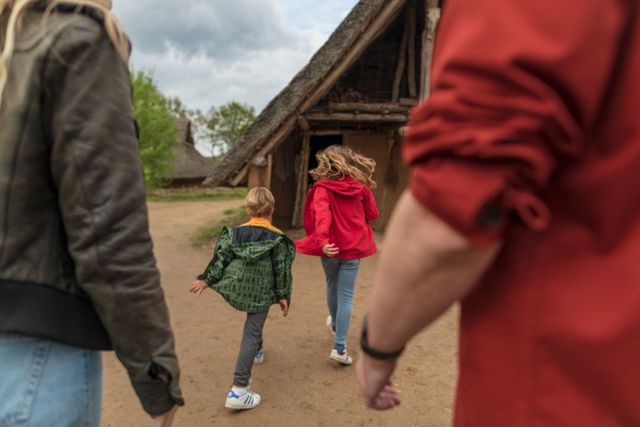 Twee kinderen lopen met hun ouders door het Oertijdpark van het Hunebedcentrum.