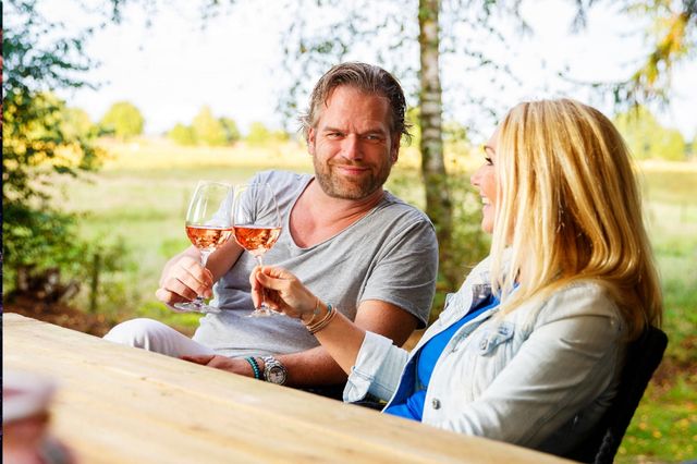 Man en vrouw proosten buiten met een glas wijn