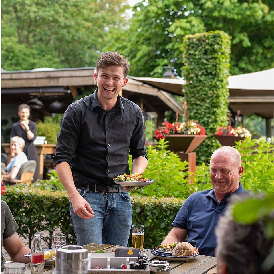 Eigenaren Rob serveert wat lekkers aan gasten op het terras van de Jacobushof