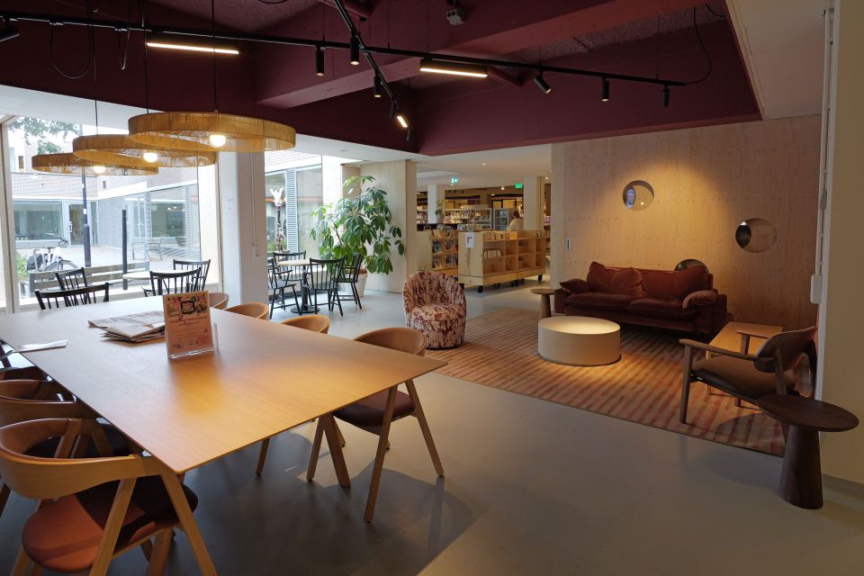 Sfeervol interieur van De Stadskamer in Woerden, met zitplekken, een grote tafel en de bibliotheek op de achtergrond.