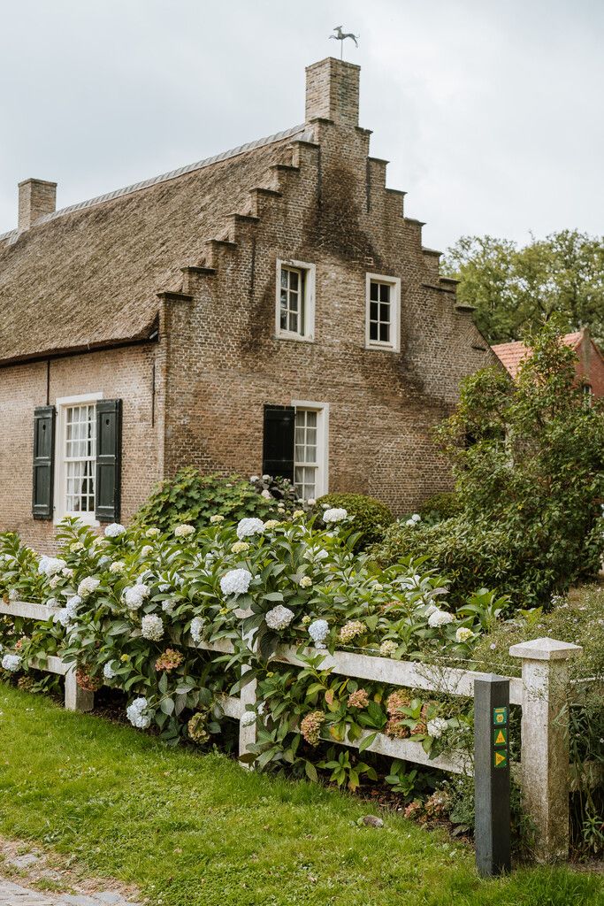 Zijaanzicht van een herberg met bloemen in de tuin.