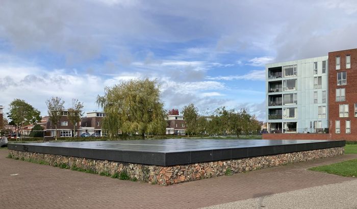 Van steen en resten van de archeologische opgravingen in een opstaand plateau gecreëerd, met stalen korf om het puin.