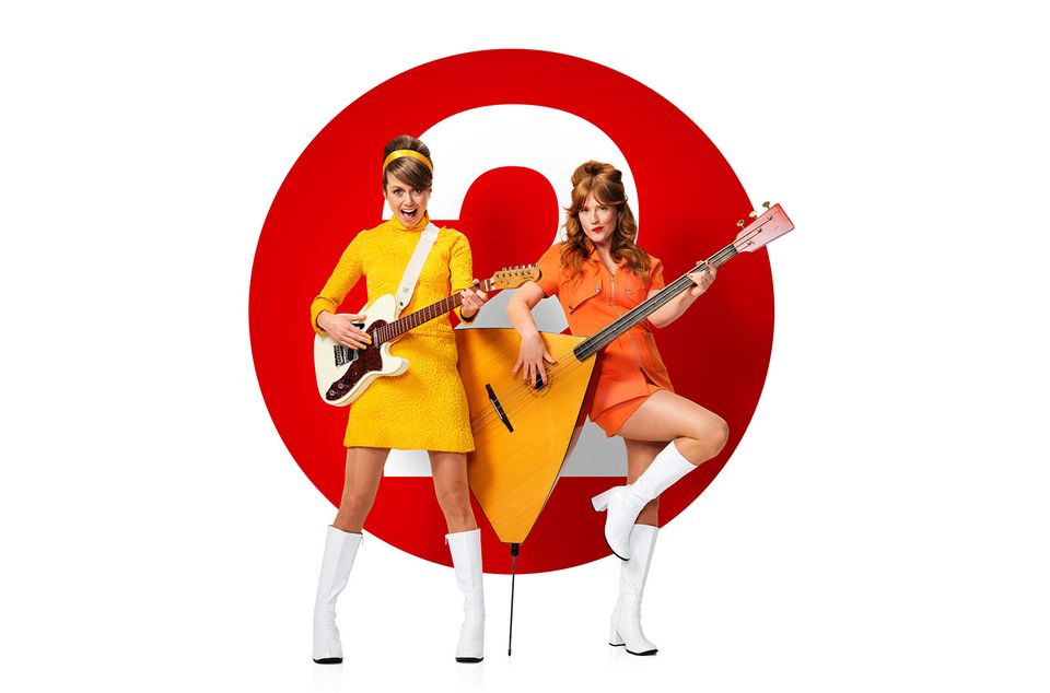 Twee vrouwen in gekleurde pakken met een muzieksintrument