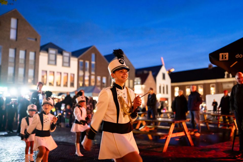 Kinderen in witte uniformen lopen tijdens een feestelijke optocht door de binnenstad van Woerden, als onderdeel van de Koetjes en Kalfjes Parade.