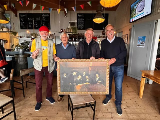 Vier oudere mannen staan in een versierd café bij een replica van een schilderij.