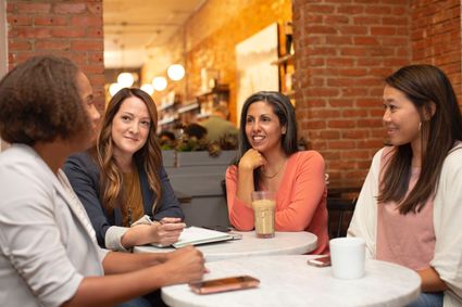 Four women sitting at a table together and talking with one another