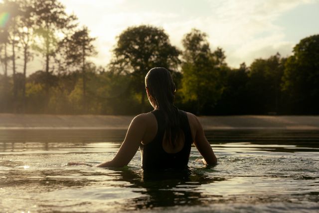 Een vrouw staat in een zwemplas in de natuur.