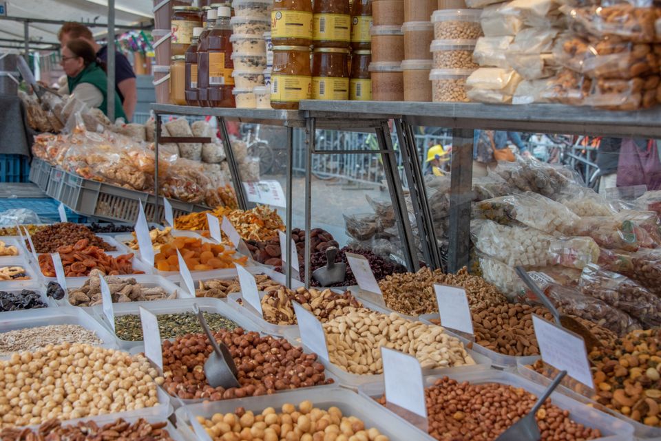 Marktkraam Streekmarkt Woerden in Woerden, Groene Hart, uitgestalde bakken met noten, pinda’s, amandelen, walnoten en gedroogde abrikozen en rozijnen, ambachtelijke delicatessen en verse streekproducten op de boerenmarkt.