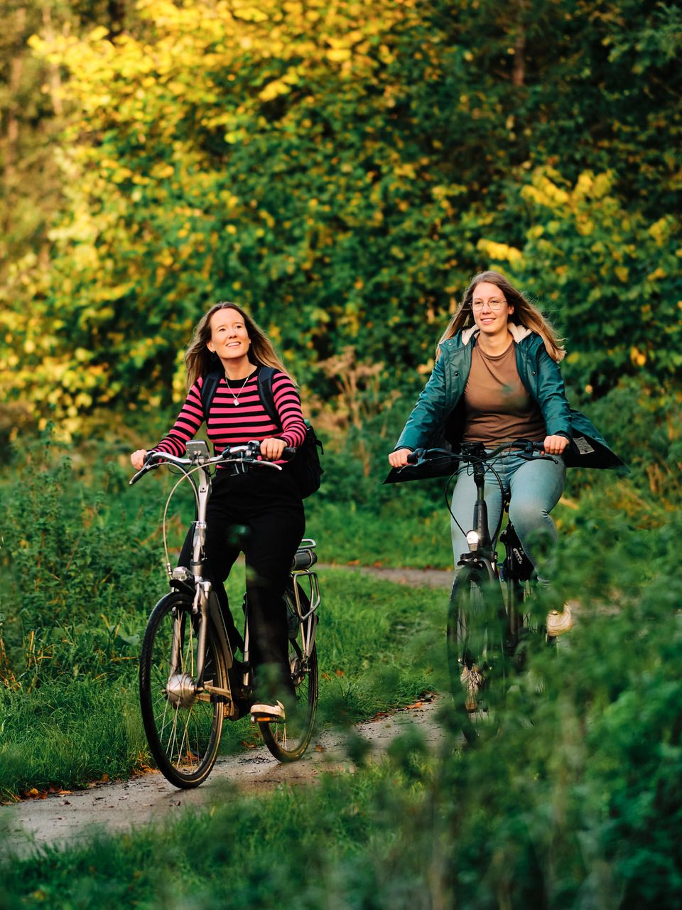 Twee vrouwen op fiets in bos.
