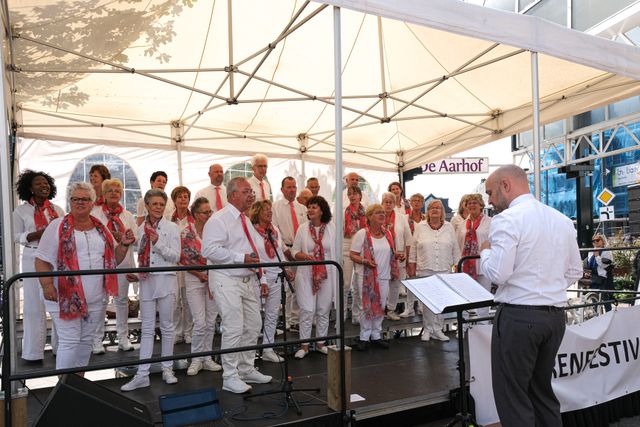 Rob van Roosmalen die zijn gospelkoor leid in een partytentje bij de Aarhof.