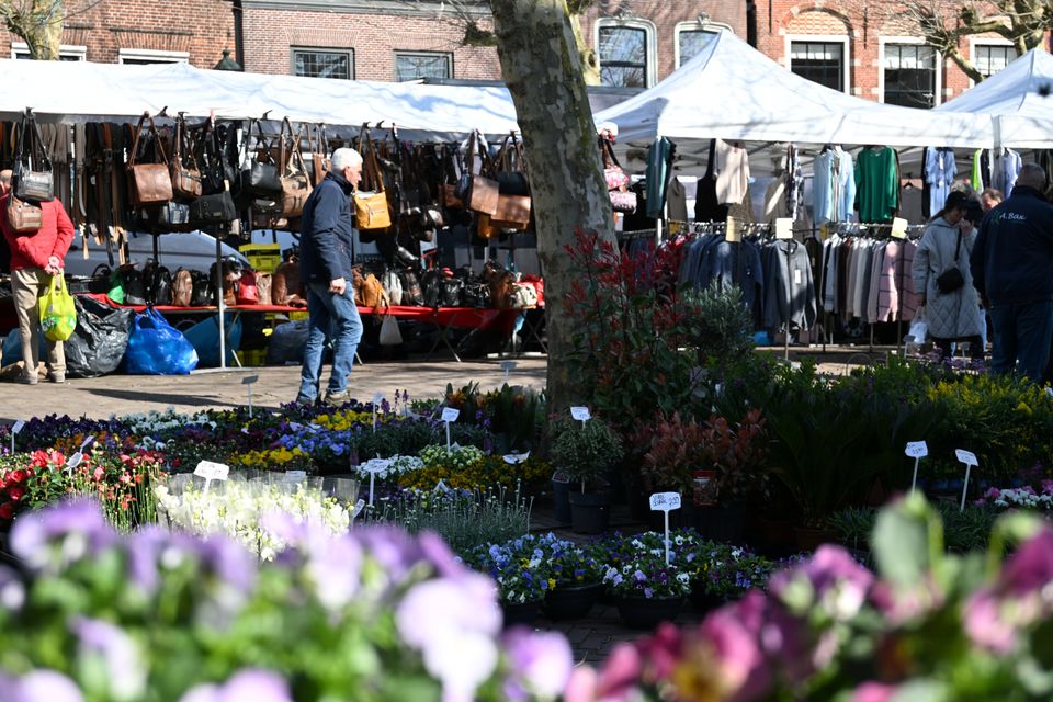 Stadscentrum weekmarkt met kramen voor kleding, tassen en bloemen/planten en winkelend publiek in Oudewater, Groene Hart.