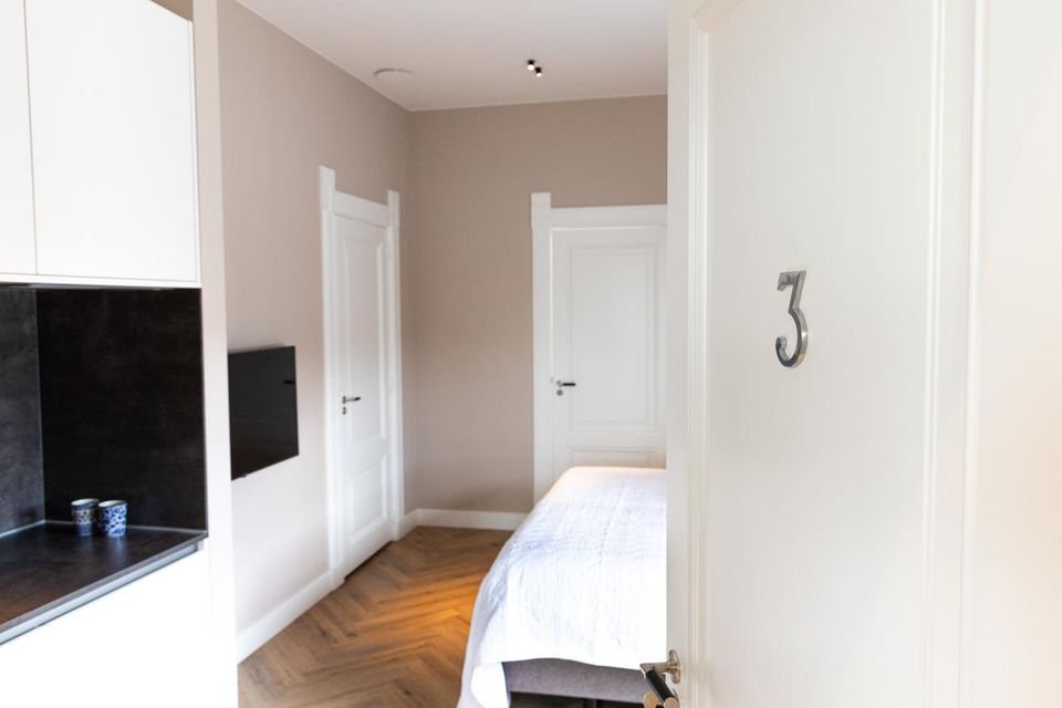 Slaapkamer van Boutique Pastorale in Montfoort met een tweepersoonsbed, lichte wanden, houten visgraatvloer en een open deur met kamernummer 3.