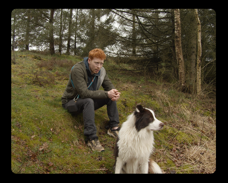 Jongeman met hond zit in een natuurgebied