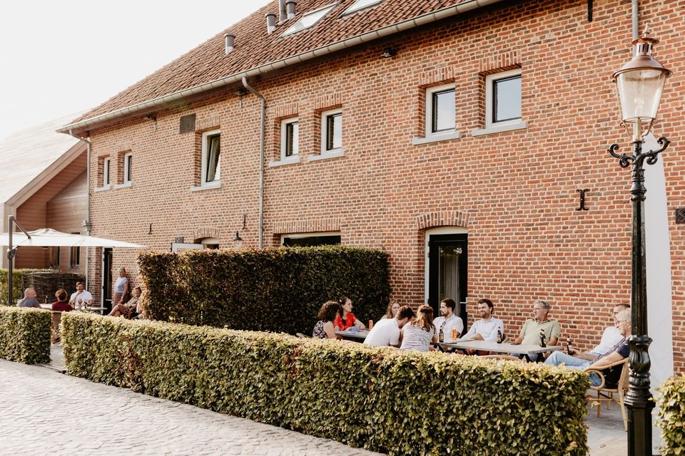 Terrasse de l' Auberge de Smockelaer avec des hôtes, située dans une authentique ferme limbourgeoise.