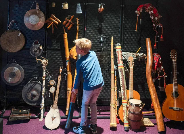 Jongetje die een wand met allerlei muziekinstrumenten bewondert