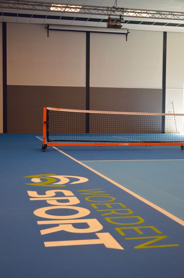 Pickleballbaan bij Zwembad H2O in Harmelen, Groene Hart, met blauw speelveld, witte belijning en pickleballnet in de overdekte sporthal.