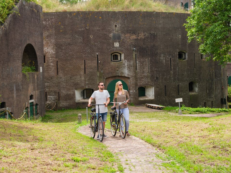 Een foto van twee personen die met de fiets aan de hand bij Fort Everdingen lopen.