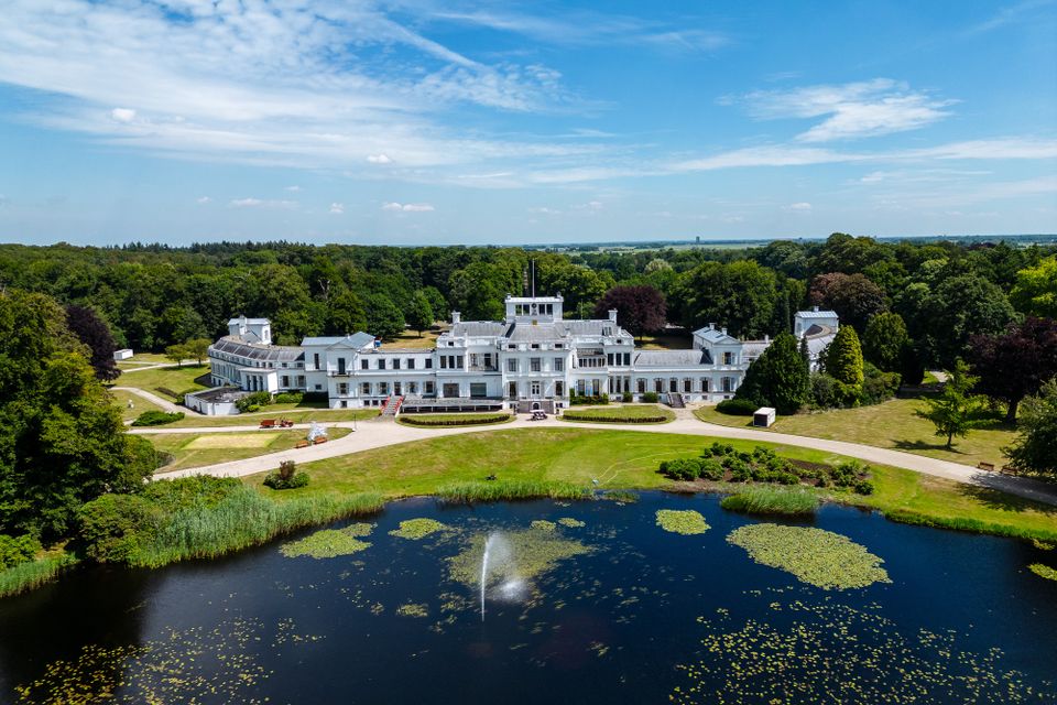 Paleis Soestdijk in combinatie met het water en de fontein. Op de achtergrond zie je het bos van de paleistuin.