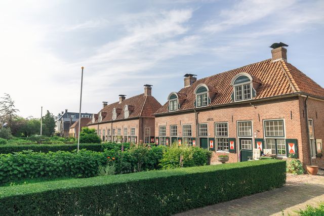 Rij historische bakstenen woningen met groene luiken en rood-witte details in Renswoude. De foto benadrukt het historische straatbeeld en het erfgoed dat verbonden is met Renswoude en de Grebbelinie.