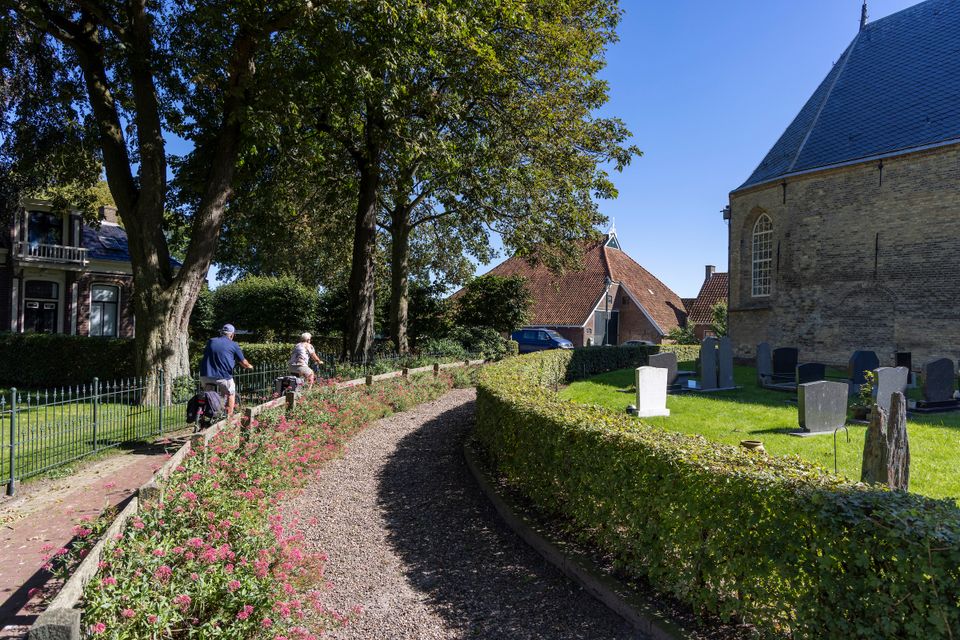 Fietsers fietsen langs het kerhof in Lytsewierrum