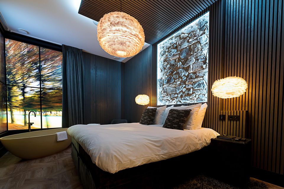 Chique, donkere hotelkamer met kingsize bed.