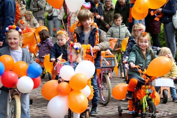 Kinderen met versierde fietsen in oranje en rood, wit en blauw kleuren