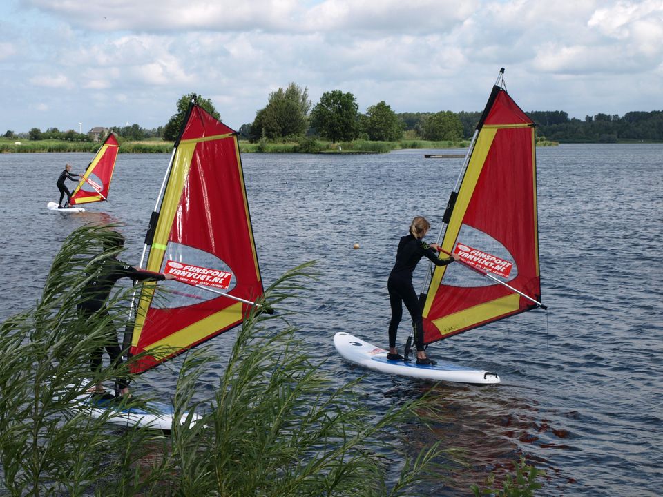 Drie windsurfers zijn bezig op het Noord Aa.