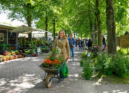 Vrouw met kruiwagen vol bloemen