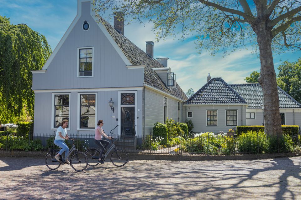 Twee fietsers fietsen door Broek in Waterland.