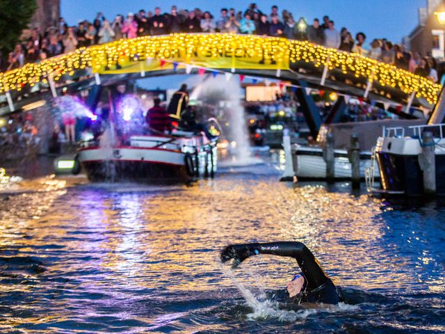verlichte brug met publiek waar Maarten van der Weijden onderdoor zwemt