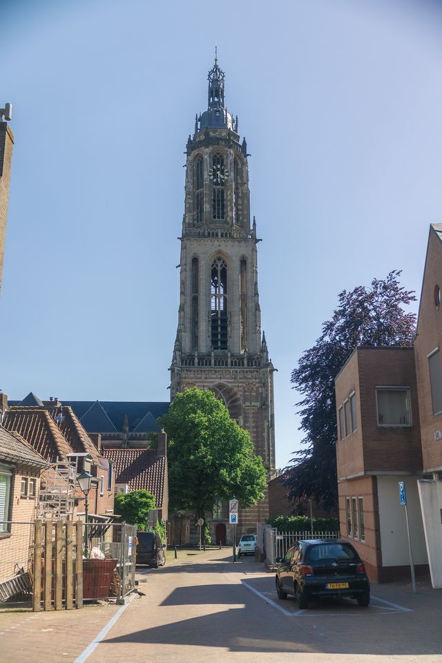 Straatje in Rhenen met uitzicht op de Cuneratoren. Er staat een auto in de straat en huizen.