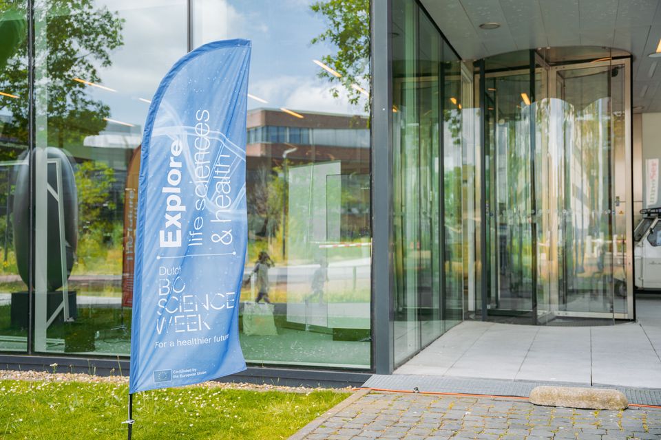 A blue Dutch Bio Science Week banner next to a door bearing the words ‘Explore Life Sciences and Health’.