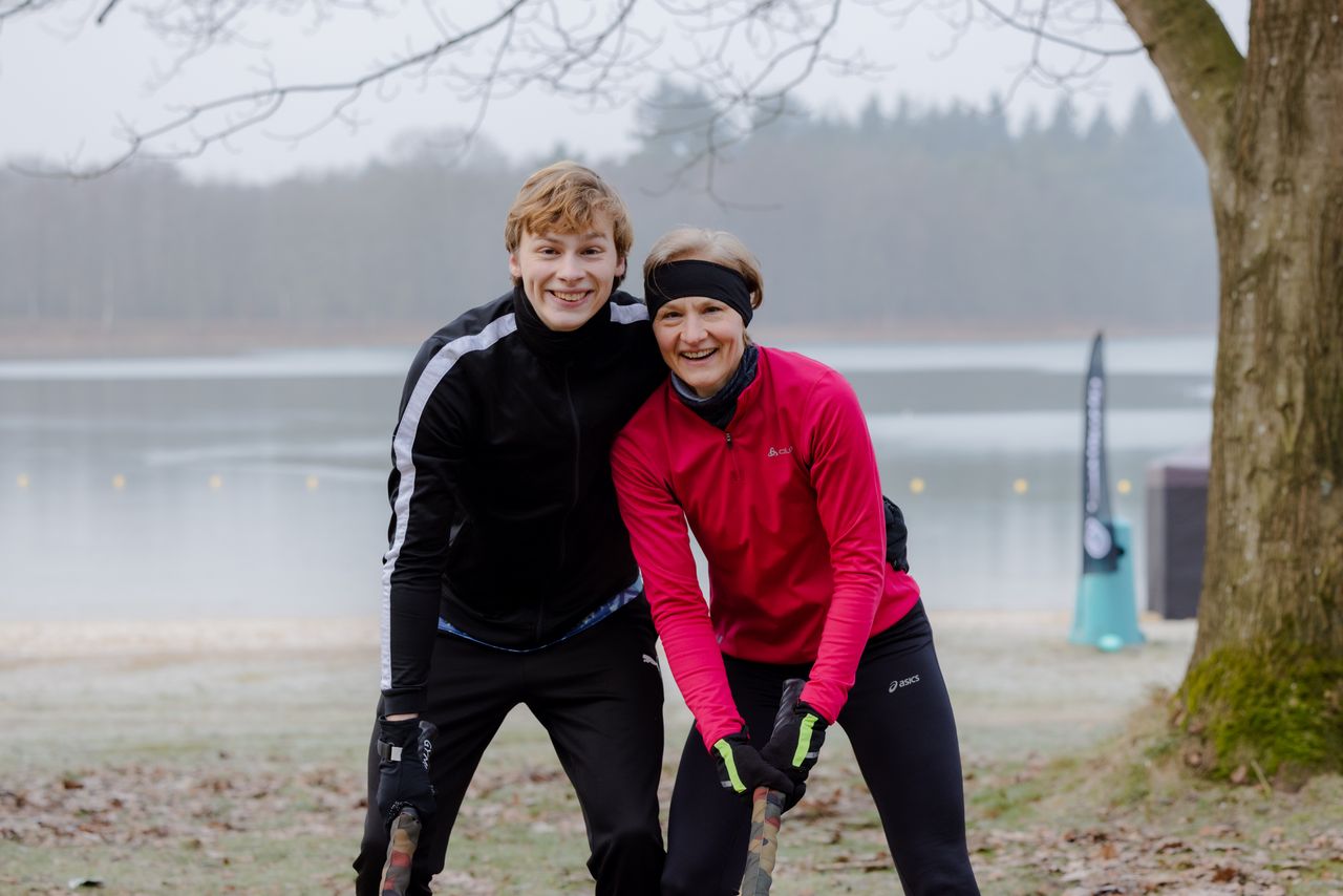 Vrouw en jongen lachend poserend voor de camera in sportkleding in de winter.