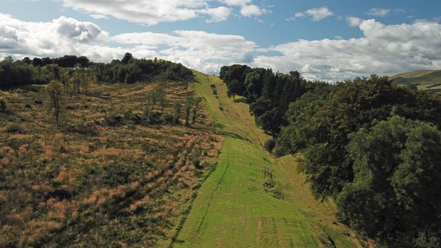 Een groen stuk van Antonine Wall, met bomen