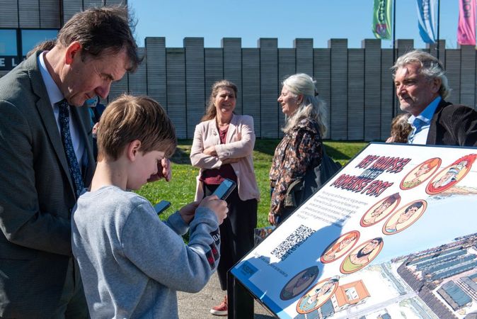 Gedeputeerde Rob van Muilekom en een jongen starten met een QR code het soundgame