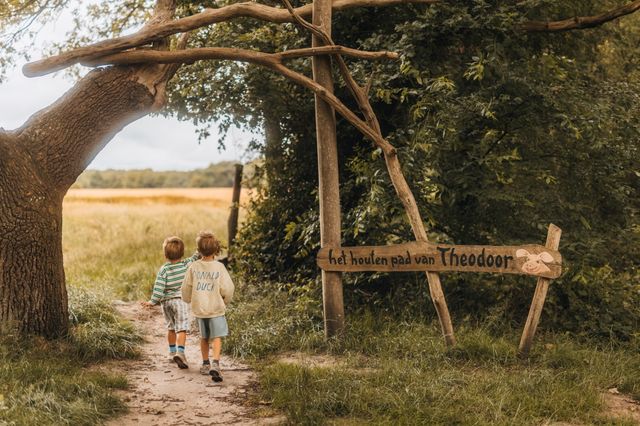Twee jongetjes lopen langs het bord van een speelbos in Drenthe.