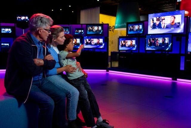 drie generaties kijken naar de installatie met 75 TV's