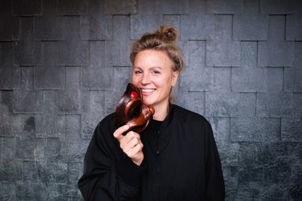 Theatervoorstelling Harlekino van Katrien van Beurden in Het Klooster Woerden, Groene Hart, met portret van de theatermaker die lachend een bruin theatermasker vasthoudt.