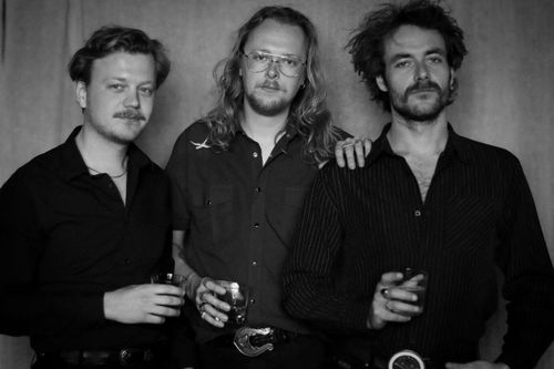 Een zwart-wit foto van 3 bandleden