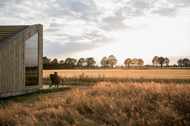 Een vrouw kijkt uit over het landschap terwijl ze op een stoel voor de trekkershut zit