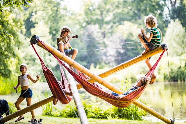 Kinderen klimmen in een bamboe-speeltoestel in het bos.