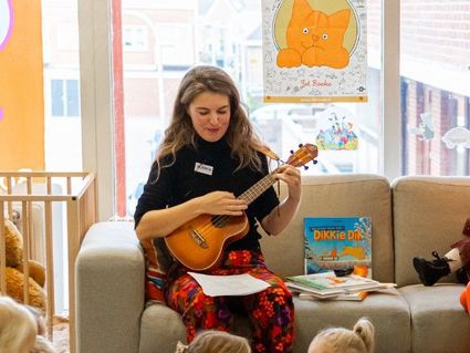 Een vrouw die de Ukelele speelt voor kinderen.