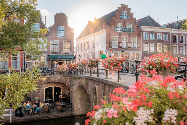 Brug over de oudegracht in Utrecht, met shoppende mensen en bloemen