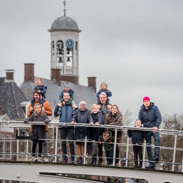 Een familiefoto op de brug tussen de Vleesmarkt en de Turfmarkt in Dokkum. Op de achtergrond het oude gemeentehuis. In verband met privacy zijn de gezichten aangepast.