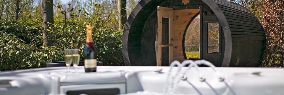 Vanuit het spa-bad met een fles champagne en 2 glaasjes kijk je op een ronde houten sauna. Bosrijke omgeving.